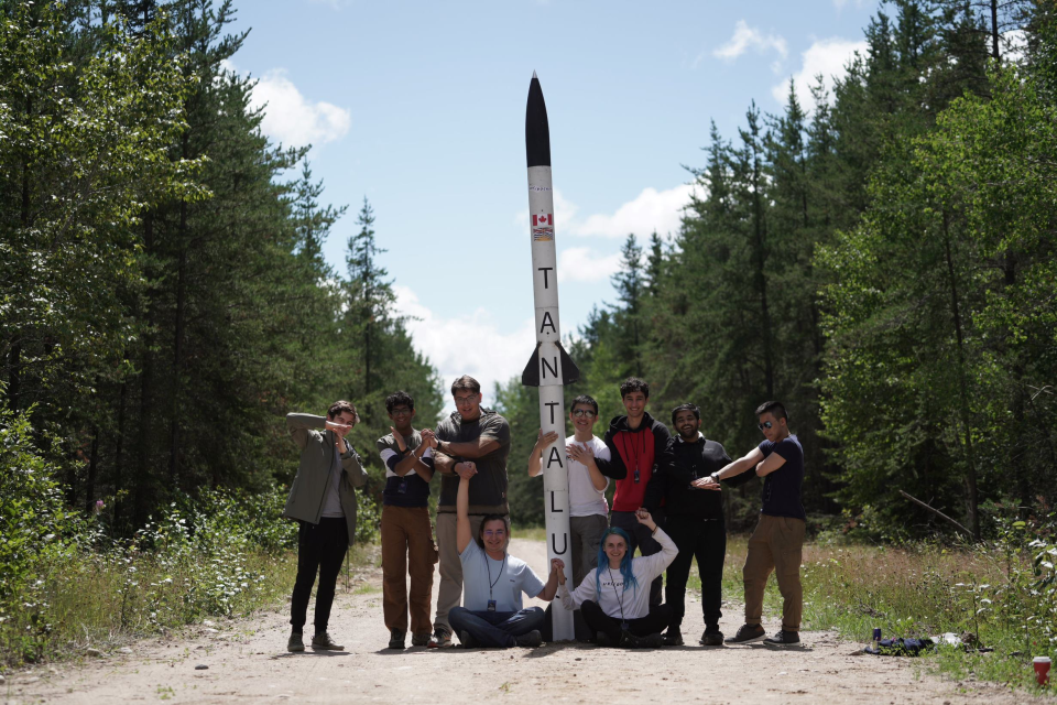 UBC Rocket students holding a rocket, Tantalus, that they made